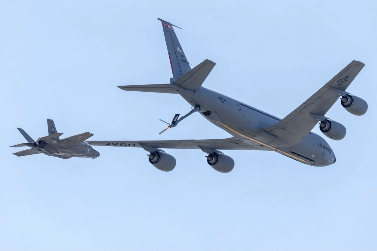 US Air Force tanker and fighter in midair refueling against a clear blue sky seen from below