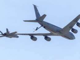 US Air Force tanker and fighter in midair refueling against a clear blue sky seen from below