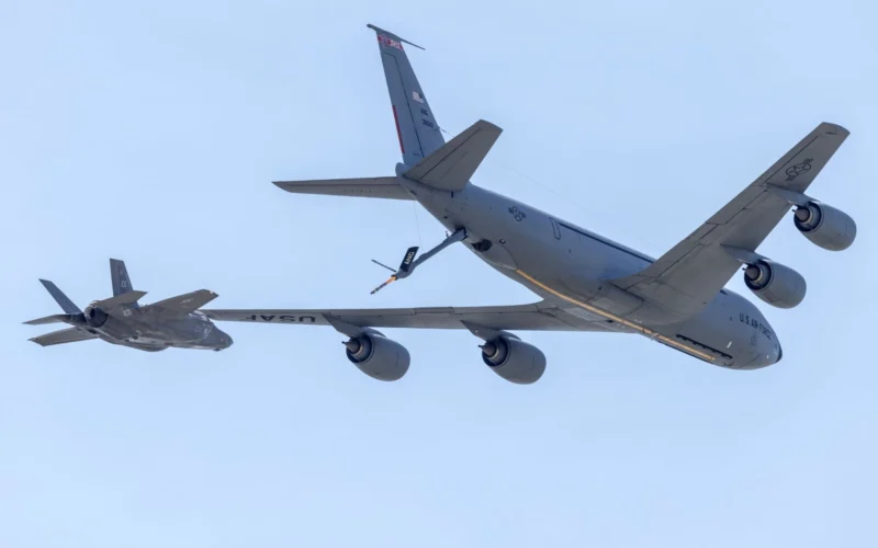 US Air Force tanker and fighter in midair refueling against a clear blue sky seen from below