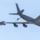 US Air Force tanker and fighter in midair refueling against a clear blue sky seen from below
