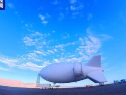 Huge white airship hovering over an airfield with mountains in the distance Chinese news logo in the top left corner