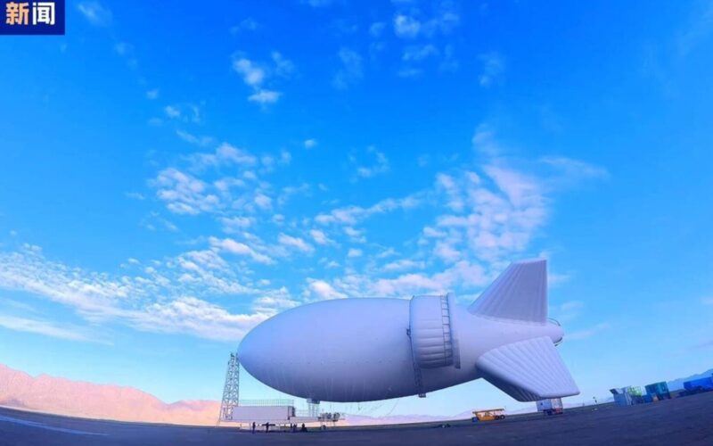 Chinas S4000 airship passes high altitude wind test Huge white airship hovering over an airfield with mountains in the distance Chinese news logo in the top left corner