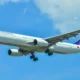Philippine Airlines wide body airliner in the sky with landing gear extended against a blue backdrop tailfin visible with colorful logo