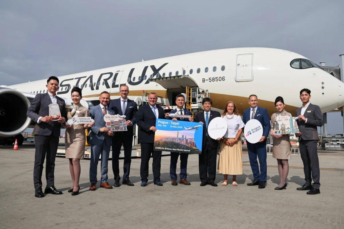 Group of airline staff and executives posing on the tarmac in front of a StarLux aircraft with travel signs