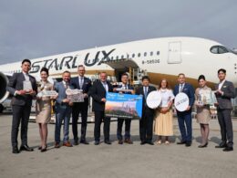 Group of airline staff and executives posing on the tarmac in front of a StarLux aircraft with travel signs