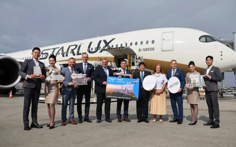 Group of airline staff and executives posing on the tarmac in front of a StarLux aircraft with travel signs