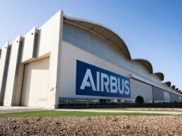 Airbus hangar with a large blue Airbus logo on the white wall under a clear blue sky