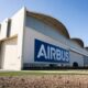 Airbus hangar with a large blue Airbus logo on the white wall under a clear blue sky