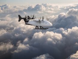 White cargo aircraft with six propellers flying above a cloudy sky labeled Zuri on the fuselage