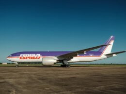FedEx Express cargo plane with purple and orange livery on a taxiway under a clear blue sky