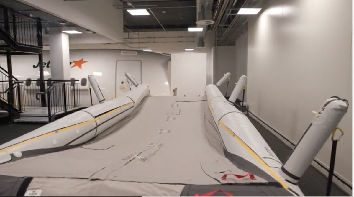 image Indoor aircraft test rig large white wing or fuselage mock up with padded curved wing sections in a hangar like facility