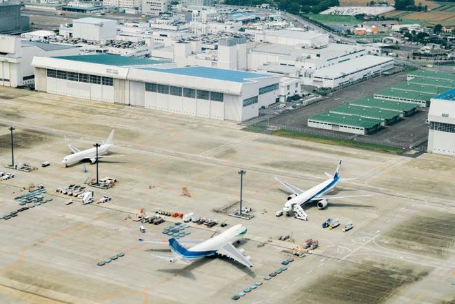 image Aerial view of a airport tarmac with three airplanes parked near cargo and service areas beside large white hangars
