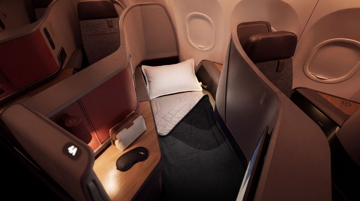 image First class airplane suite with a reclined bed white pillow and warm cabin lighting