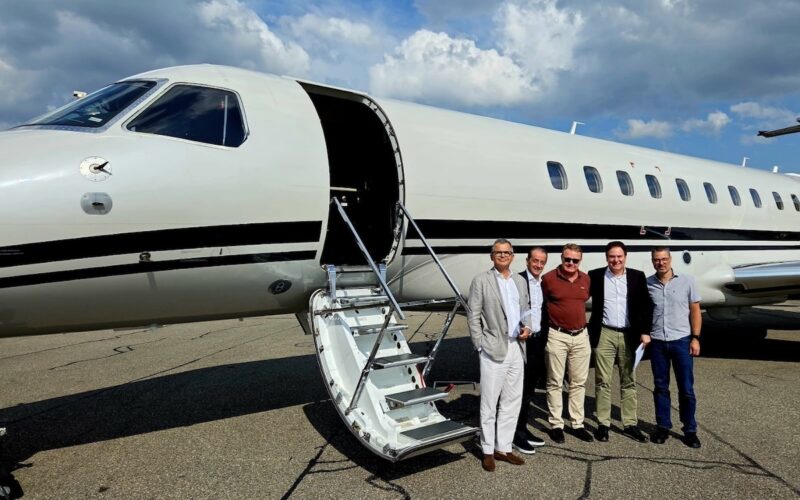 peakjet first flight Five men in smart casual attire pose beside a white private jet with its door open and a portable staircase on the tarmac