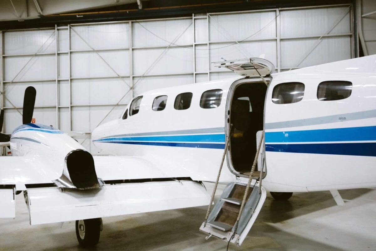 security aviation cover 1600x1000jpeg White private jet with blue stripes inside a hangar stairs deployed at the open door