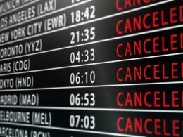 Flight status board showing multiple flights with many as CANCELLED red across routes like Los Angeles New York City Toronto Paris Tokyo Madrid etc