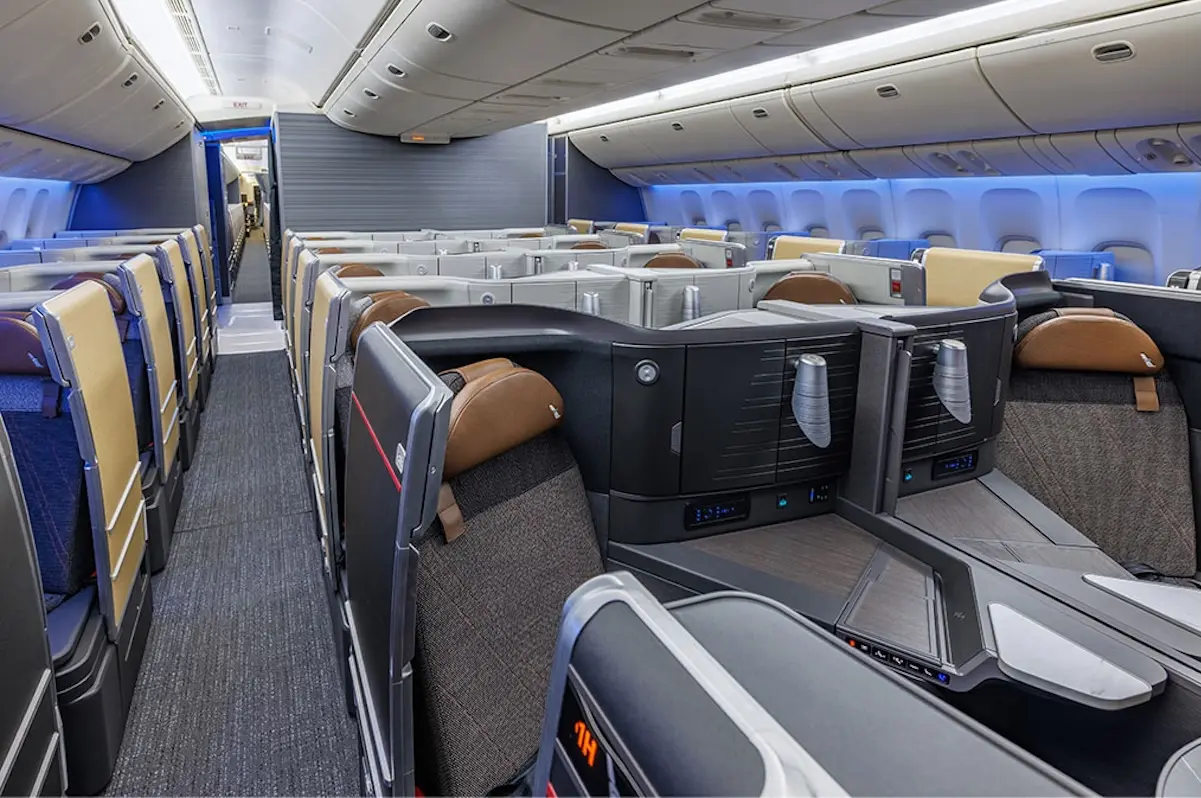 090226 777 300 retrofit FSC v2 Interior of a modern airplane in business class showing private lie flat seats and partitioned pods with blue ambient lighting facing forward