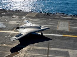 A gray F 35B stealth jet on the deck of an aircraft carrier with the ocean in the background
