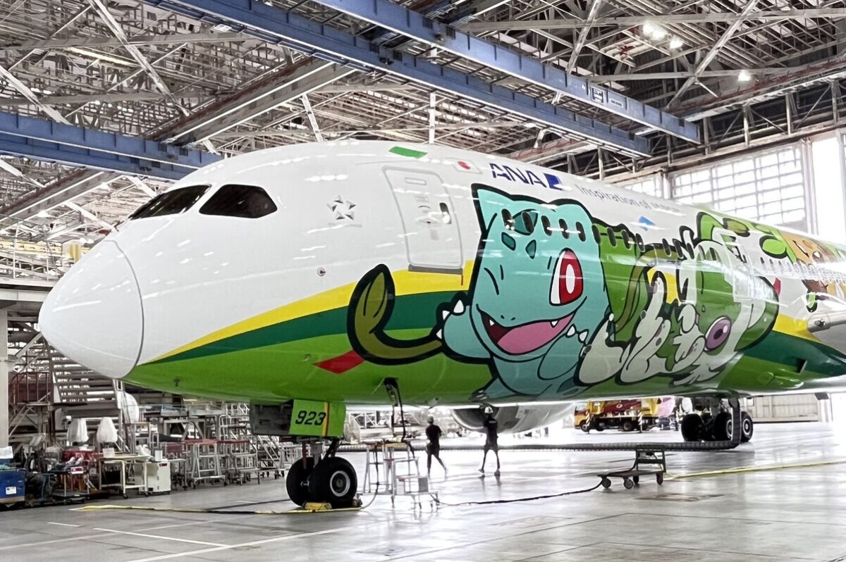 1789707019047 Airliner inside a maintenance hangar with a bright green and blue cartoon dragon mural along the fuselage