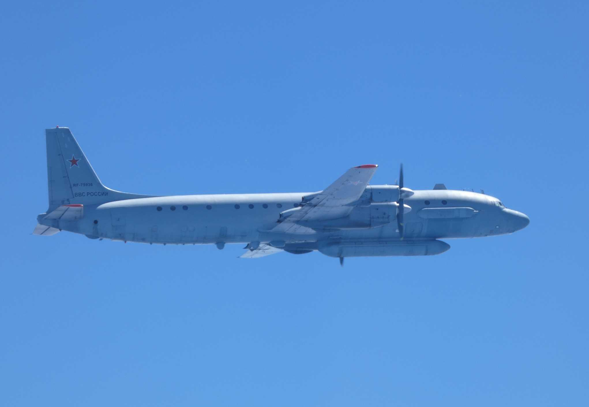 Military transport aircraft flying low over blue sky Russia Air Force star insignia on tail