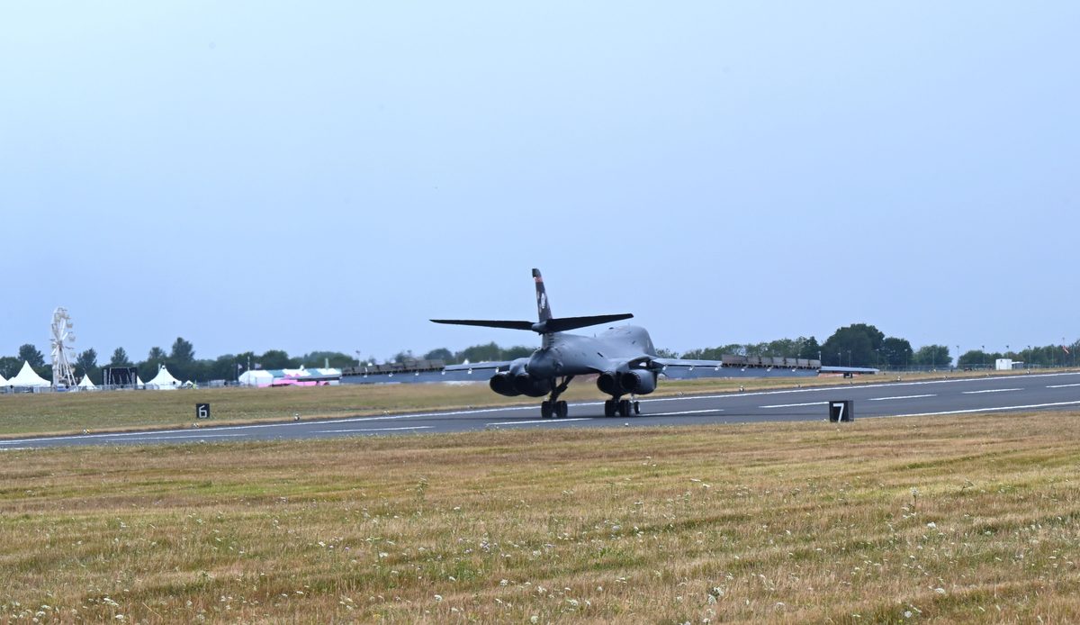 US Air Force B 1B Lancer arrives at RAF Fairford to support RIAT 2025 Military bomber taxiing on runway at an airshow with tents and a ferris wheel in the background