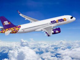 Air Cairo passenger jet flying above the clouds with purple logo and yellow purple tail design visible