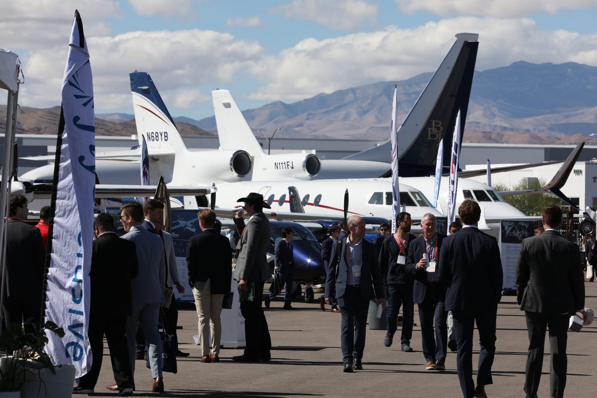 Aircraft Connection Close Up Crowd of professionals at an airshow with private jets on display and mountains in the distance
