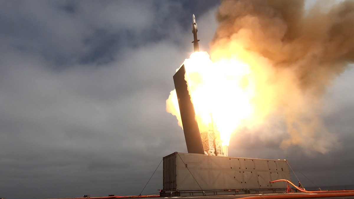 USS Savannah Conducts Live Fire Demonstration Rocket lifting off from a launch pad with bright flames and thick smoke surrounding the booster