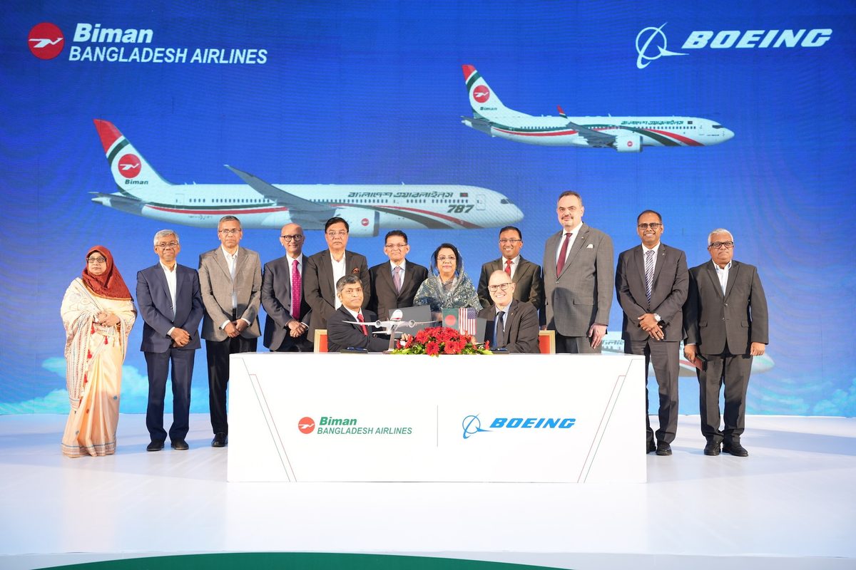 Boeing and Biman Bangladesh Airlines Group of officials at a signing ceremony on a stage with a model airplane and red flowers on the desk backdrop shows Biman Bangladesh Airlines and Boeing logos