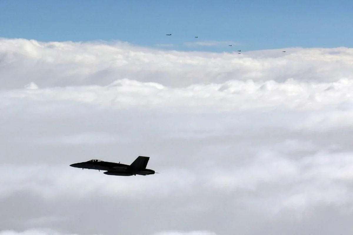 Finnish Air Force FA 18 Hornet flies alongside a formation of Russian military aircraft over the Gulf of Finland