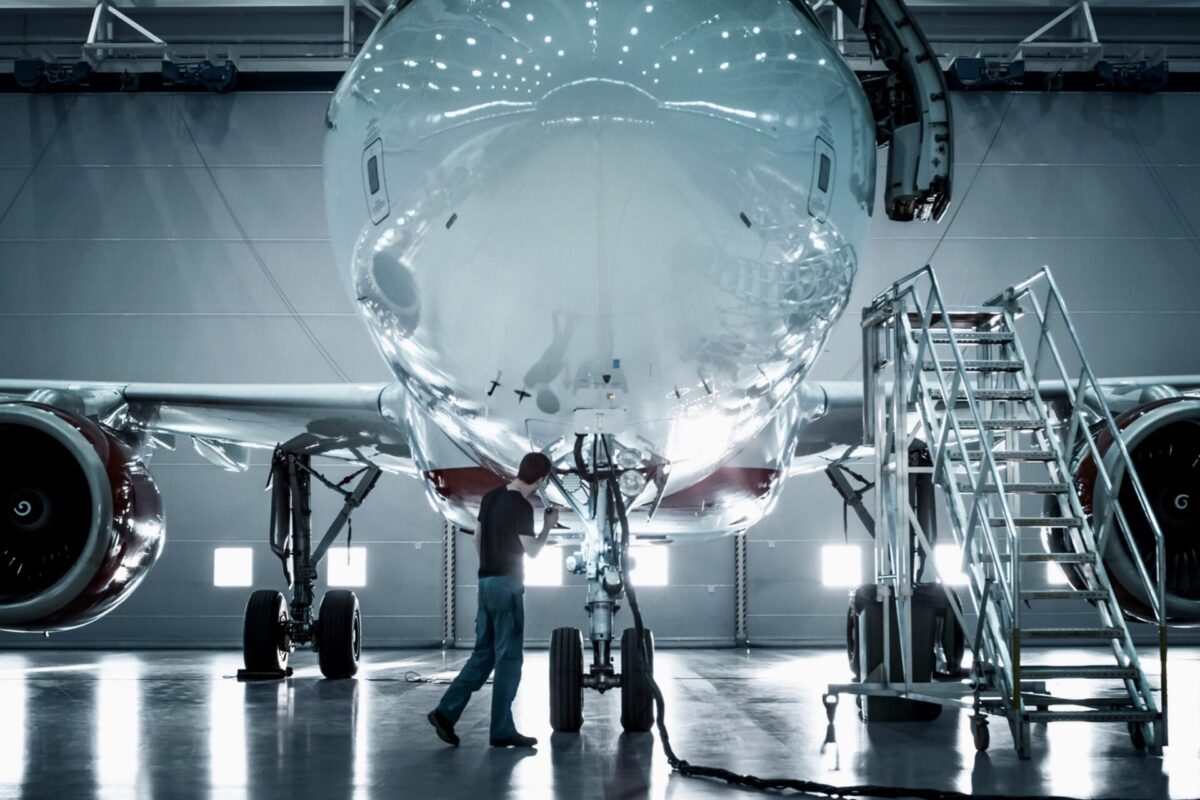 Recently Saved 1 of 1 1 Technician inspecting the nose of a large jet in a hangar with mobile stairs nearby during maintenance
