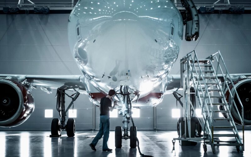 Recently Saved 1 of 1 1 Technician inspecting the nose of a large jet in a hangar with mobile stairs nearby during maintenance
