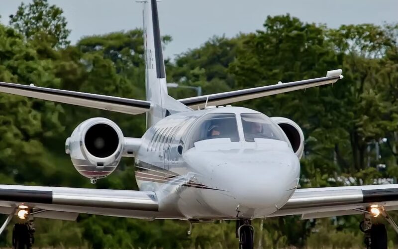 Recently Saved 1 of 1 18 Front view of a white private jet with side mounted engines landing gear down taxiing on a runway with green trees in the background