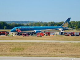 Vietnam Airlines plane on the tarmac surrounded by multiple red emergency vehicles and ground crew at an airport