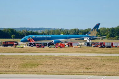 Vietnam Airlines plane on the tarmac surrounded by multiple red emergency vehicles and ground crew at an airport