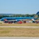 Vietnam Airlines plane on the tarmac surrounded by multiple red emergency vehicles and ground crew at an airport