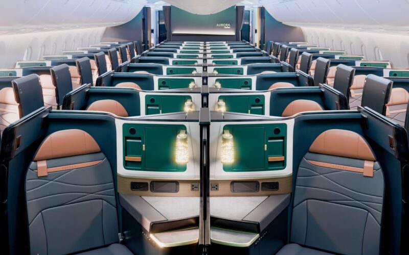 Recently Saved 1 of 1 24 Wide view of a modern airplane cabin with private business class suites teal storage panels and peach seats along a long aisle