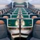 Wide view of a modern airplane cabin with private business class suites teal storage panels and peach seats along a long aisle