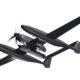 Twin fuselage unmanned aerial vehicle drone with a long wing and vertical tail shown in flight against a white background from a top right perspective