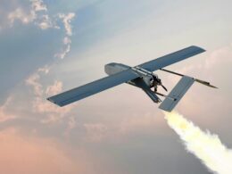 Small unmanned aircraft in flight against a pastel sky with a bright exhaust trail behind it