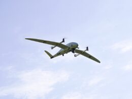 Small twin engine propeller airplane flying in a clear blue sky from a below view