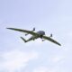Small twin engine propeller airplane flying in a clear blue sky from a below view