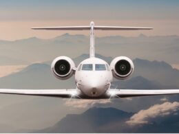 Front on view of a white passenger jet approaching the camera with mountains and clouds in the background during flight