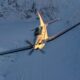 White single engine airplane banking over a snow covered mountain landscape at sunset