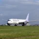 Riyadh Air widebody airplane taxiing on a runway with a purple tailed livery and a control tower in the distance