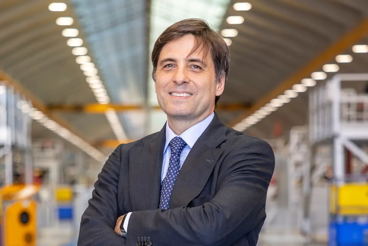 Stefano Villanti Professional man in a dark suit with arms crossed in a bright industrial warehouse