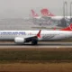 Turkish Airlines Boeing 737 Max taxiing on the runway fuselage marked TURKISH AIRLINES with a red tail logo in the background