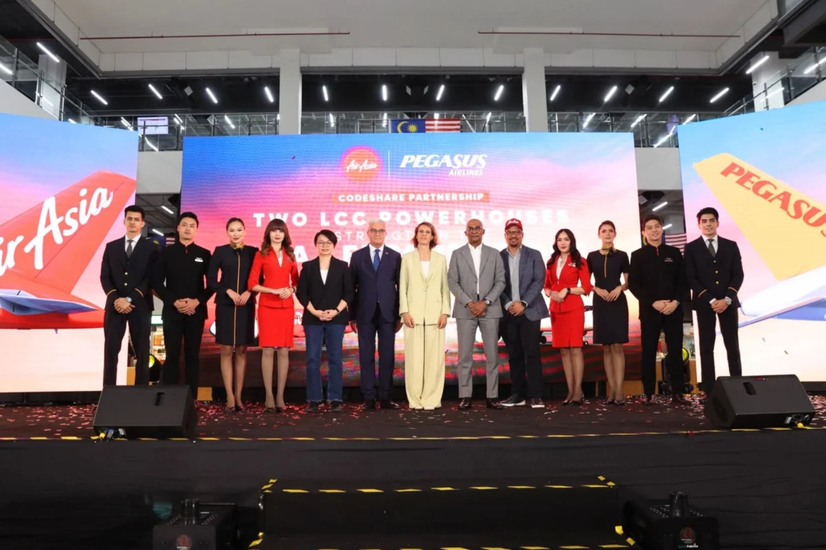 Group of professionally dressed individuals standing on a stage for a formal event with a large LED backdrop displaying Two LCC Powerhouses and brand logos behind them