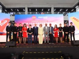 Group of professionally dressed individuals standing on a stage for a formal event with a large LED backdrop displaying Two LCC Powerhouses and brand logos behind them