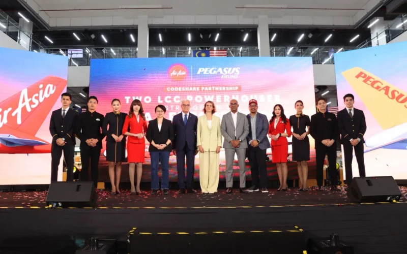 Group of professionally dressed individuals standing on a stage for a formal event with a large LED backdrop displaying Two LCC Powerhouses and brand logos behind them